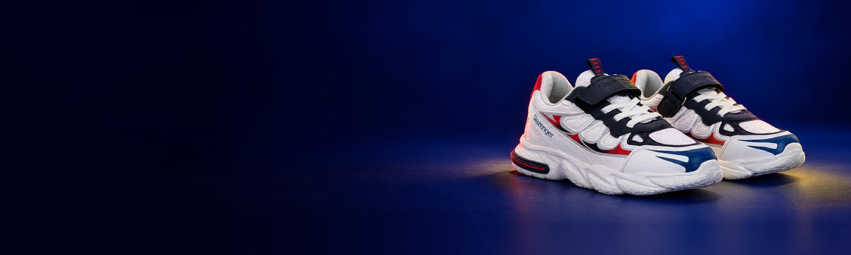 White and navy Slazenger Kafka kids' sneakers with a hook-and-loop strap on a dark navy background