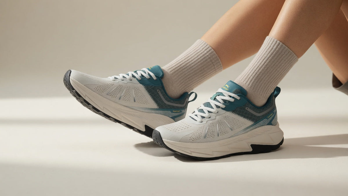 Person seated with legs crossed, wearing white and teal Slazenger Warren sneakers and cream socks