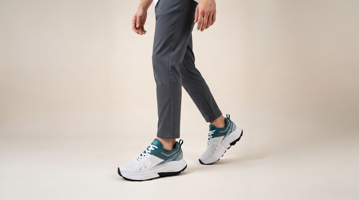 A man walking in white Slazenger Warren sneakers with green panels, against a pale studio background