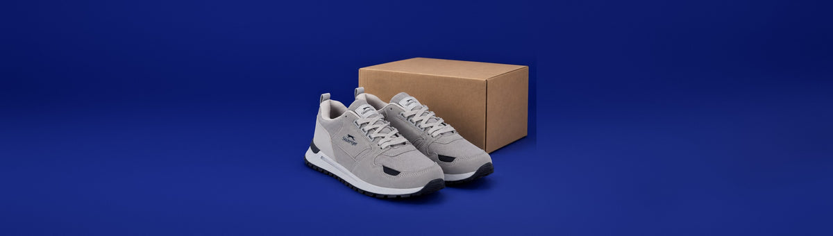 Slazenger Preston sneakers beside a cardboard shipping box on a navy background