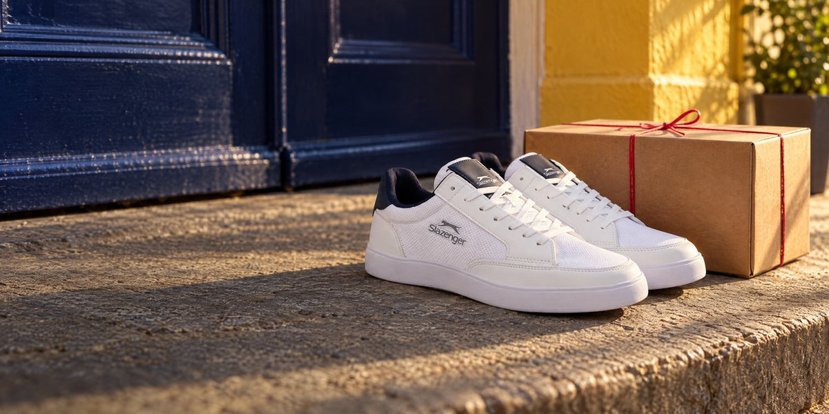 White Slazenger sneakers on a sunny doorstep next to a parcel tied with red string